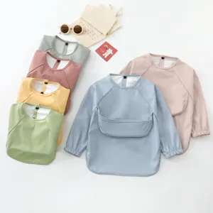 Waterproof baby feeding smock with long sleeves and catch-all pocket in multiple pastel colors.