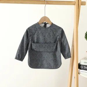 Grey long sleeve baby waterproof bib, cute cartoon face print, toddler feeding apron.