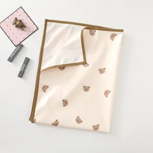 Waterproof baby changing mat detail view, beige pad with brown border and cute bear print.