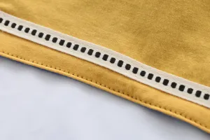 Gros plan détaillé du tissu de bavette pour bébé avec une belle texture jaune et bordure décorative.