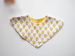 Detailed view of baby triangle bib, soft cotton fabric with yellow floral print, snap button.
