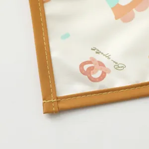 Closeup of waterproof baby mat edge, neat yellow stitching and cute printed cartoon pattern.
