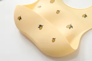 Silicone baby bib detail view featuring cute lemon print waterproof food catcher pocket design.