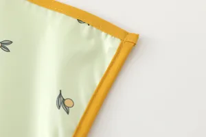 Close-up detail of waterproof baby urine mat with yellow border and cute fruit pattern.