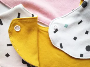 Detailed view of soft cotton baby drool bib with geometric patterns and secure snap button.
