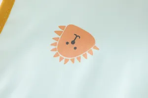 Close-up detail of baby waterproof bib featuring a cute cartoon lion pattern in light green.