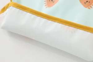 Waterproof baby feeding bib detail view with cute cartoon print and yellow trim.