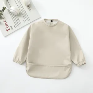 Babero impermeable manga larga bebé beige delantal alimentación detalle primer plano