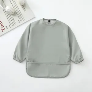 Detalle del babero impermeable para bebé de manga larga con práctico bolsillo atrapa migas.