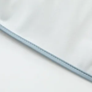 Primer plano del borde del babero impermeable para bebé, costuras finas y tela resistente.