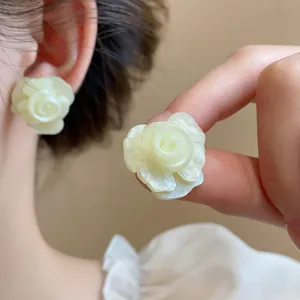 Nahaufnahme der eleganten mehrschichtigen weißen Rosenblüten-Ohrstecker, sanfter Stil.