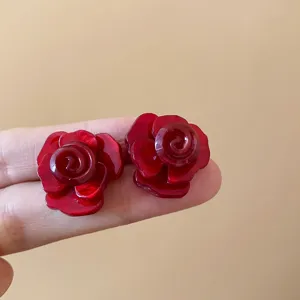 Nahaufnahme der dunkelroten mehrschichtigen Rosen-Ohrstecker mit elegantem Detaildesign.