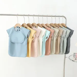 Waterproof PU short sleeve baby feeding bib with double-breasted design and pocket.