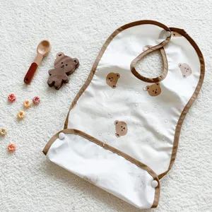 Waterproof baby feeding bib detail with cute bear print and deep crumb catcher pocket.