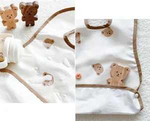 Detailed view of waterproof baby feeding bib with cute bear print and brown trim.