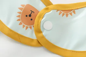 Waterproof baby bib detail shot, light blue with cute orange sun cartoon print and yellow edge.