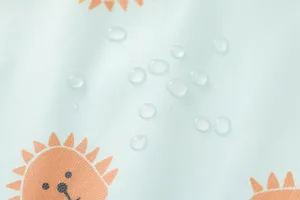 Waterproof baby bib detail shot featuring cute cartoon lion pattern and water droplets.