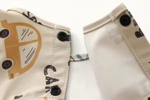 Close-up detail of waterproof baby bib with cute car print and durable snap buttons.
