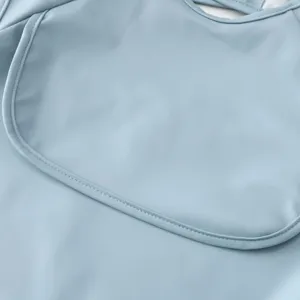 Waterproof baby feeding bib detail shot, soft PU material with neat stitching, light blue color.