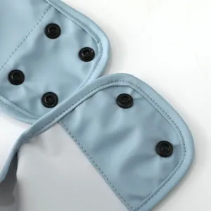 Baby bib detail shot, light blue PU material with black snap buttons, close-up view.