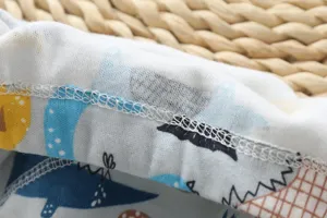 Vue rapprochée du tissu de pantalon d'entraînement pour bébé en coton avec imprimé dinosaure.