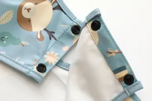 Detailansicht des wasserdichten Langarm-Baby-Lätzchens mit süßem Print und sicheren Druckknöpfen.