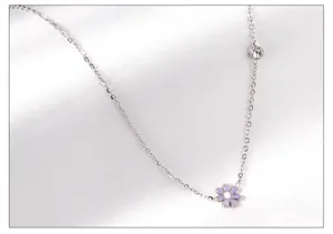 Close-up of a delicate stainless steel chain necklace featuring a purple enamel daisy pendant.