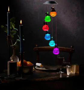 Solar powered Halloween pumpkin wind chime light glowing in a dark rustic dining room setup