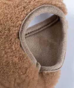 Gros plan détail emmanchure gilet polaire animal, tissu thermique marron doux et chaud.