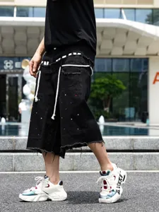 Pantaloncini di jeans neri da uomo con strass colorati, bordi grezzi e coulisse bianche.
