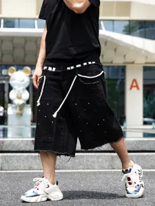 Primo piano di pantaloncini di jeans neri da uomo con strass colorati e bordi sfrangiati.