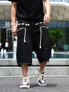 Vista dettagliata di pantaloncini in denim nero da uomo con orlo vivo, strass colorati e coulisse.