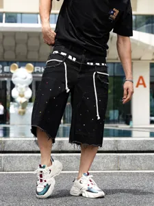 Shorts in denim nero da uomo con strass colorati e bordi sfrangiati in stile hip-hop moderno.