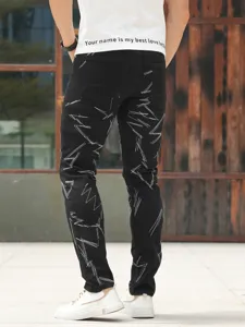 Back detail of men's slim fit black washed jeans with unique white embroidery design.