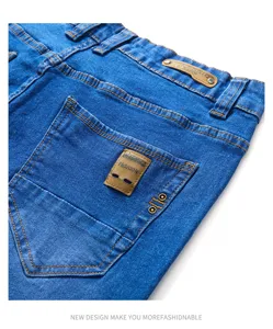 Detailed view of men's blue denim jeans back pocket with contrast stitching and metal rivets.