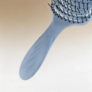 Close-up detail shot of the curved hair brush showing the ergonomic handle and bristles.