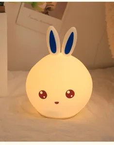 Close-up of a cute silicone bunny night light emitting a warm yellow glow.