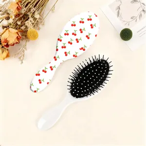 Detail view of the cherry print oval cushion hair brush showing pattern and bristles clearly.