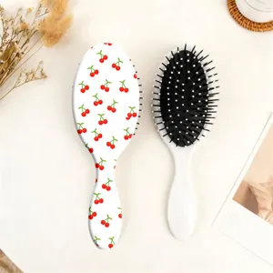 Detailed view of the cute cherry print oval cushion hair brush with soft bristles for daily hair care.