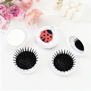 Vue détaillée de la brosse à cheveux pliante portable avec miroir intégré et motif coccinelle mignon.