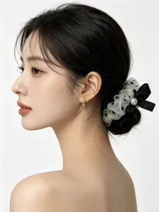 Λεπτομερής λήψη υφασμάτινου scrunchie μαλλιών με πουά σχέδιο, φιόγκο και πέρλα.