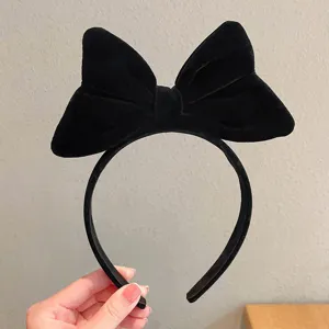 Close-up detail of a black velvet bow headband, showing soft texture and elegant hair accessory.