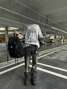 Streetwear style distressed micro-flared jeans and graphic long sleeve t-shirt outfit detail.