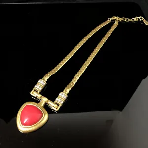 Vintage gold necklace with red triangle pendant and crystal details for elegant women.