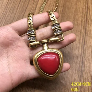 Detailed shot of vintage gold chain necklace with red stone pendant and sparkling rhinestones.