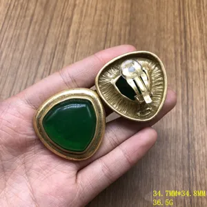 Vintage green stone triangle clip earrings detail shot, textured gold metal design.