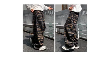 Jean baggy homme streetwear noir avec imprimé graffiti de lettres dorées sur toute la surface.