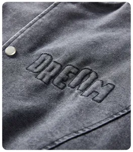 Dettaglio tessuto giacca da baseball casual uomo, in cotone grigio lavato vintage e ricamo.