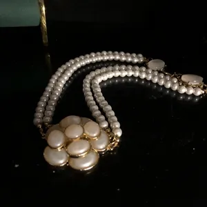 Primer plano detallado del collar de perlas de doble capa vintage con colgante camelia.