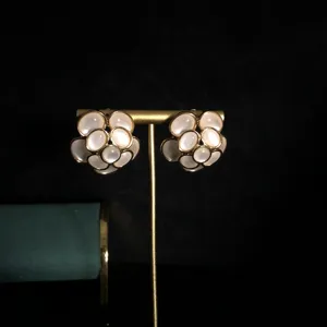 Primer plano detallado de pendientes de botón de camelia vintage con piedras cabochon.